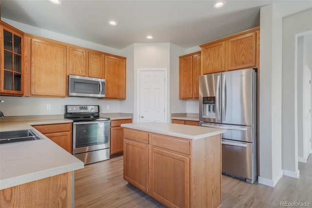 kitchen featuring stainless steel appliances, a center island, sink, and light wood-type flooring