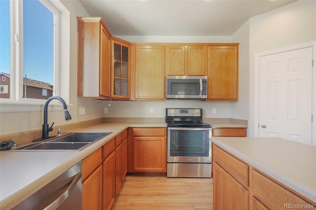 kitchen featuring appliances with stainless steel finishes, sink, and light hardwood / wood-style floors