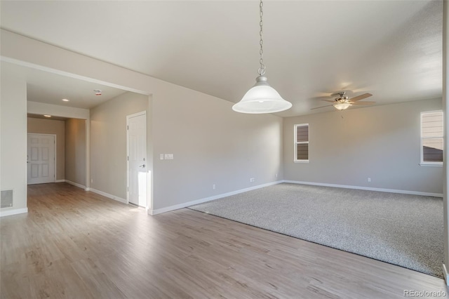 empty room with ceiling fan and light hardwood / wood-style flooring