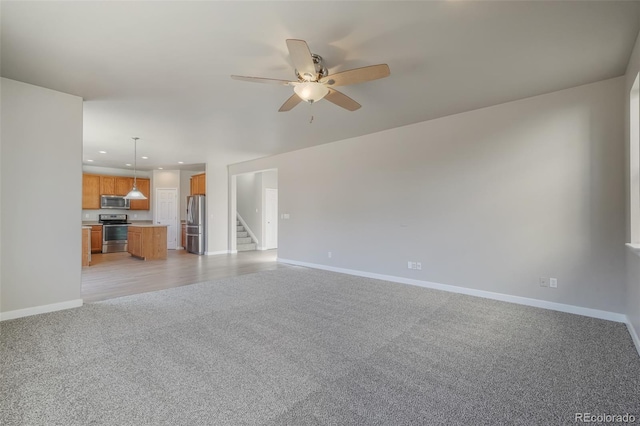 unfurnished living room featuring light colored carpet and ceiling fan