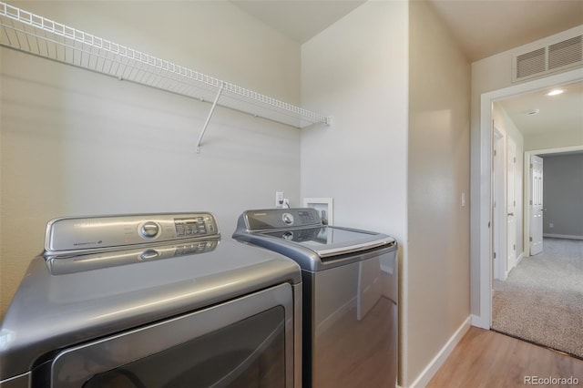 laundry area with independent washer and dryer and light wood-type flooring