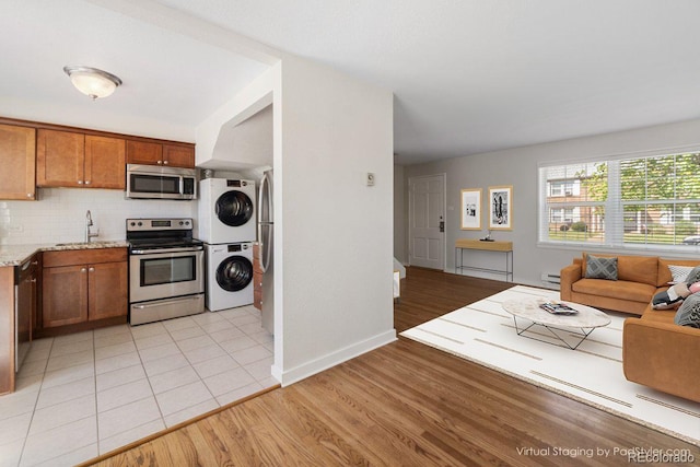 2872 Jasmine St, Denver, CO 80207 - kitchen with stainless steel appliances, stacked washer / dryer, a sink, a baseboard heating unit, and backsplash