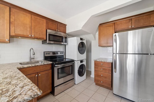 2872 Jasmine St, Denver, CO 80207 - kitchen featuring stainless steel appliances, a sink, stacked washer / drying machine, and brown cabinets