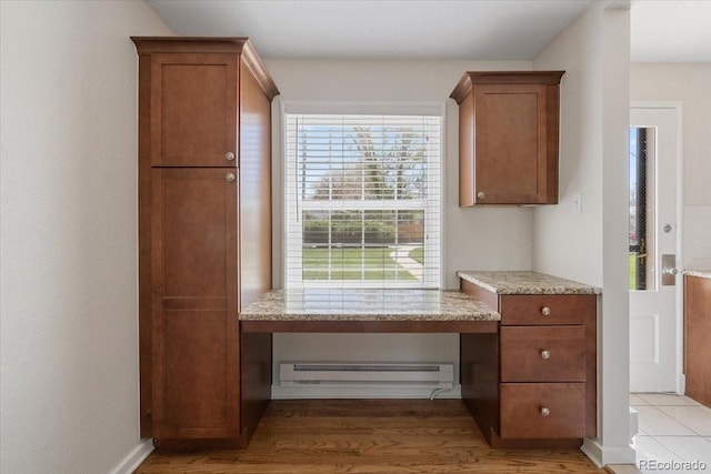 2872 Jasmine St, Denver, CO 80207 - kitchen featuring a baseboard heating unit, brown cabinets, light wood-type flooring, and light stone counters