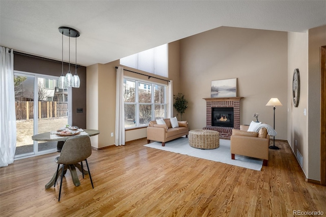 living room with visible vents, a healthy amount of sunlight, a fireplace, and light wood finished floors