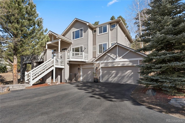 rustic home with aphalt driveway, an attached garage, and stairway