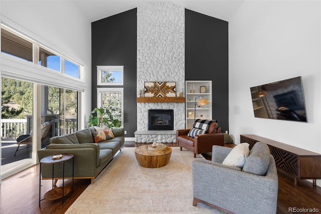 living room featuring high vaulted ceiling, wood finished floors, and a fireplace