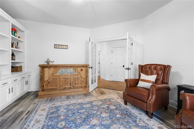 living area with wood finished floors, baseboards, and french doors