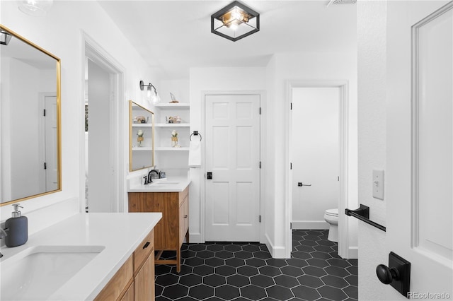 bathroom featuring a sink, visible vents, toilet, and two vanities