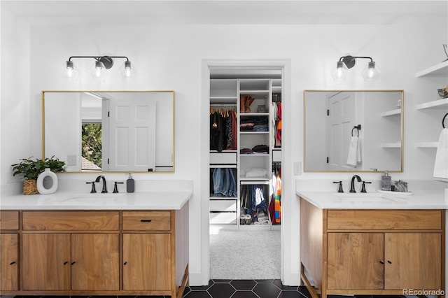 bathroom featuring a sink, a walk in closet, and two vanities