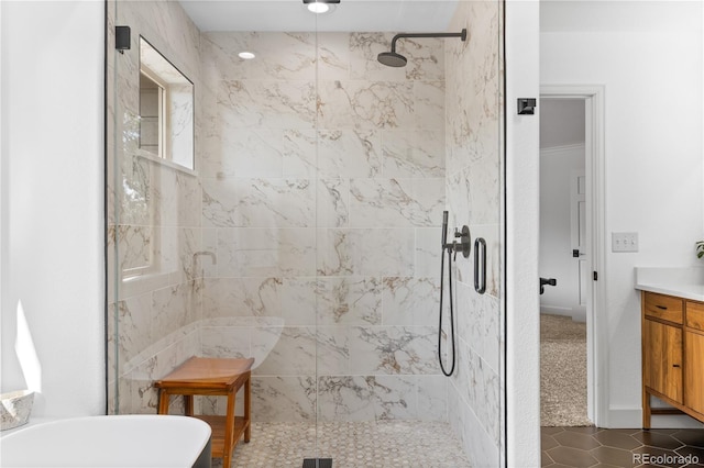 bathroom with a freestanding bath, vanity, tile patterned flooring, and tiled shower