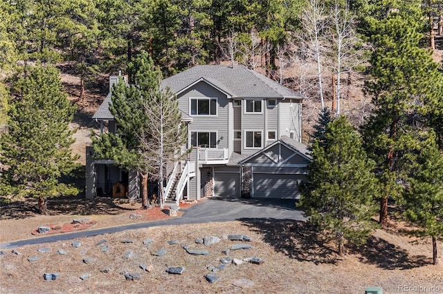 view of front of home with aphalt driveway, a garage, stairs, and a shingled roof