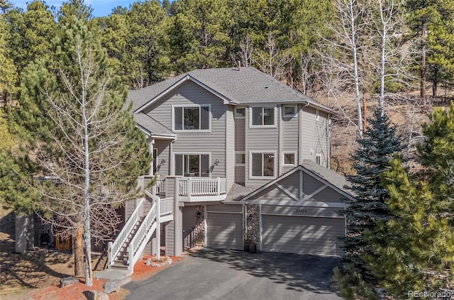 view of front of house featuring stairs, aphalt driveway, an attached garage, and roof with shingles