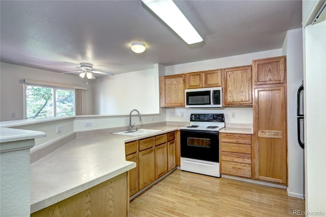 1997 E 102nd Cir, Thornton, CO 80229 - kitchen featuring range with electric cooktop, stainless steel microwave, a peninsula, light countertops, and light wood-style floors