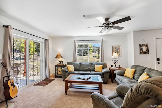 living area with light colored carpet, a wealth of natural light, and a ceiling fan
