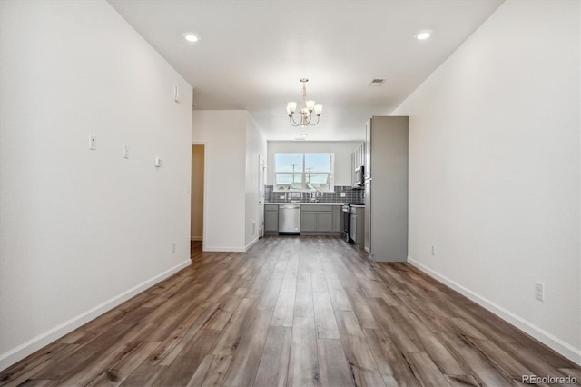 unfurnished living room featuring dark hardwood / wood-style floors and an inviting chandelier