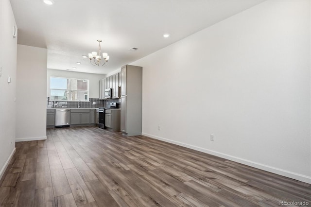 unfurnished living room with a notable chandelier and dark hardwood / wood-style floors