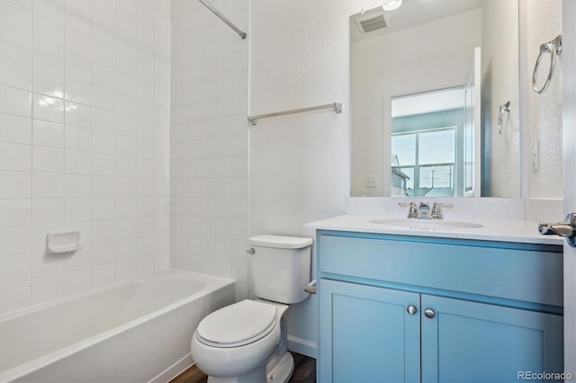 full bathroom featuring tiled shower / bath, vanity, and toilet