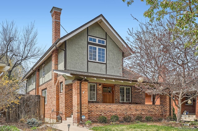 821 S High St, Denver, CO 80209 - view of front of property featuring a chimney, stucco siding, brick siding, covered porch, and fence
