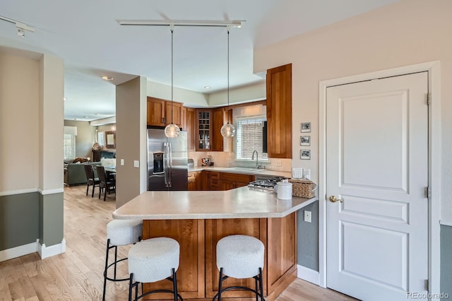 821 S High St, Denver, CO 80209 - kitchen with stainless steel appliances, a sink, brown cabinetry, a peninsula, and plenty of natural light