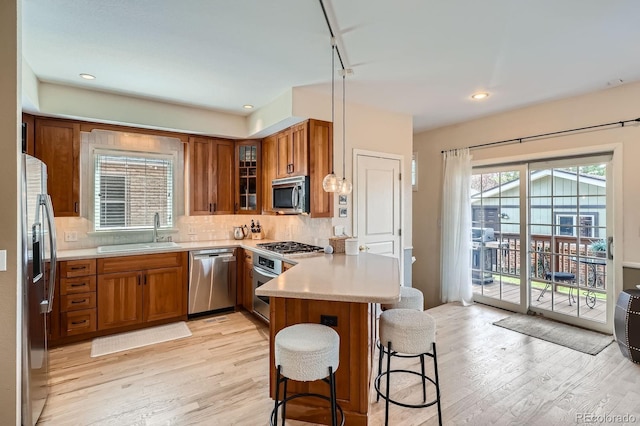 821 S High St, Denver, CO 80209 - kitchen with appliances with stainless steel finishes, a sink, brown cabinetry, a peninsula, and recessed lighting