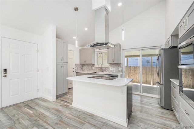 kitchen featuring appliances with stainless steel finishes, a sink, extractor fan, gray cabinets, and light wood-type flooring