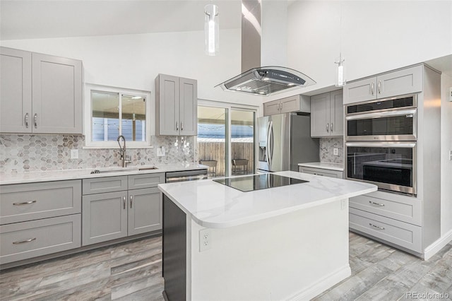 kitchen featuring island range hood, gray cabinetry, a sink, light wood-style floors, and stainless steel appliances
