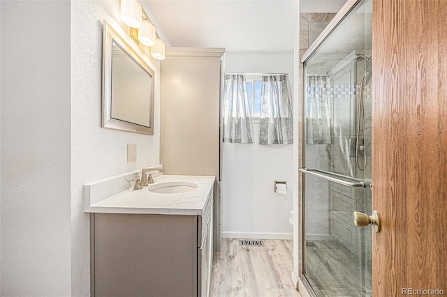 bathroom featuring toilet, a shower stall, wood finished floors, and vanity