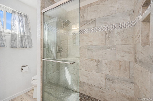 full bathroom with baseboards, a shower stall, and toilet