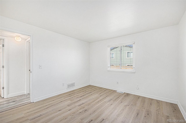 empty room featuring visible vents, baseboards, and light wood-type flooring