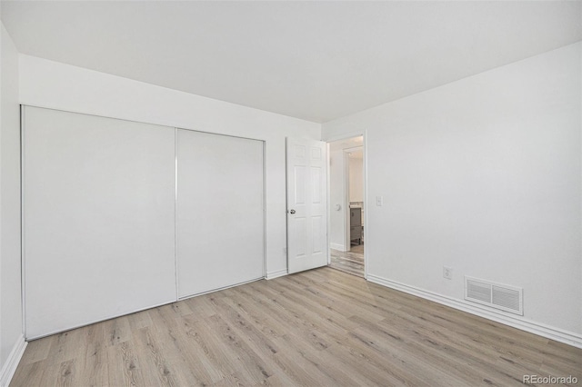 unfurnished bedroom featuring visible vents, light wood-style floors, baseboards, and a closet