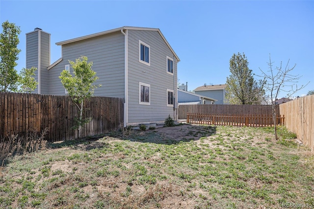 exterior space featuring a fenced backyard, a chimney, and a lawn