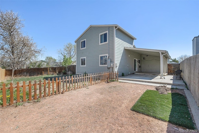 rear view of house with dirt driveway and a fenced backyard