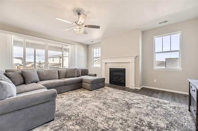 living room with ceiling fan, dark wood-type flooring, and a brick fireplace