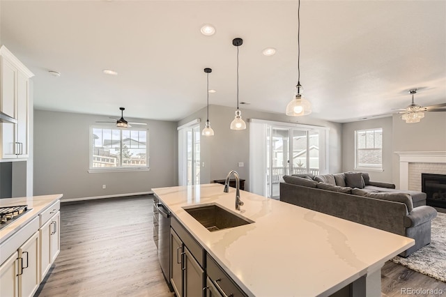 kitchen with pendant lighting, light stone countertops, sink, and an island with sink