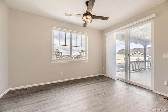 empty room with ceiling fan, wood-type flooring, and a wealth of natural light