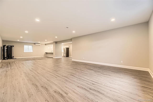 unfurnished living room with an AC wall unit and light hardwood / wood-style flooring