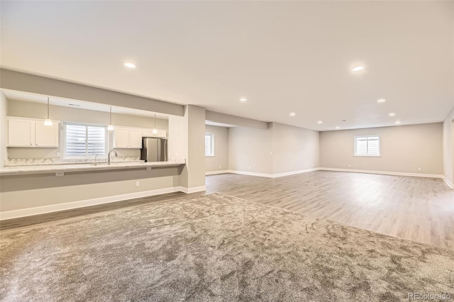 basement with light hardwood / wood-style floors, stainless steel refrigerator, and sink