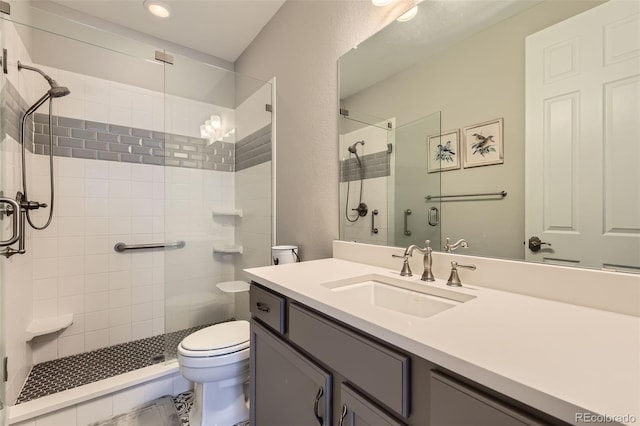 bathroom featuring a shower with door, vanity, and toilet