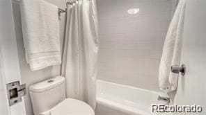 bathroom featuring shower / bath combo with shower curtain and toilet