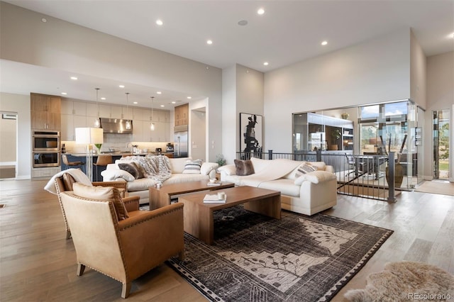 living room featuring a towering ceiling and light hardwood / wood-style floors