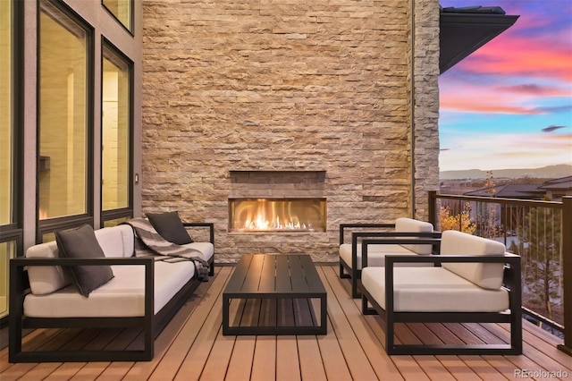 deck at dusk with an outdoor living space with a fireplace