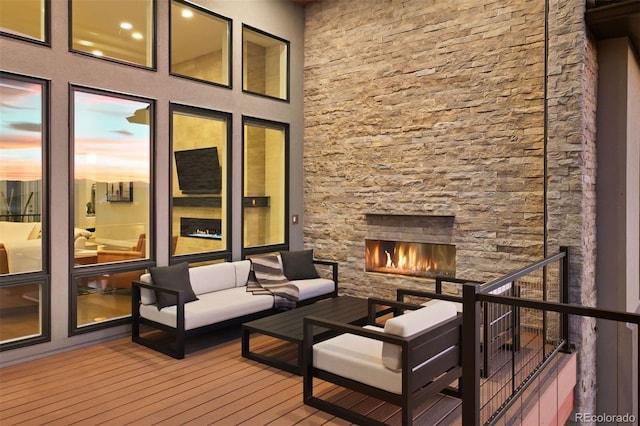 deck at dusk with an outdoor living space with a fireplace