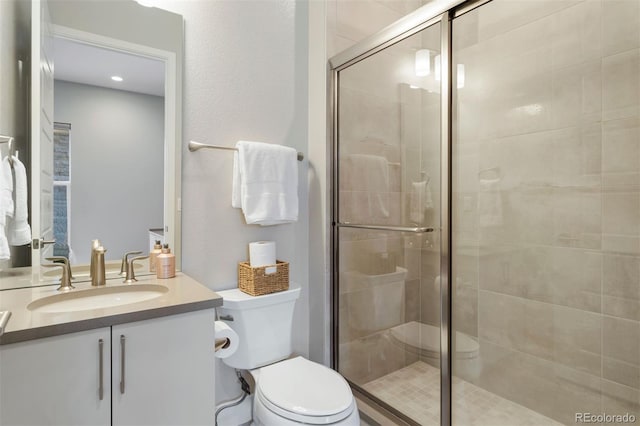 bathroom with vanity, a shower with door, and toilet