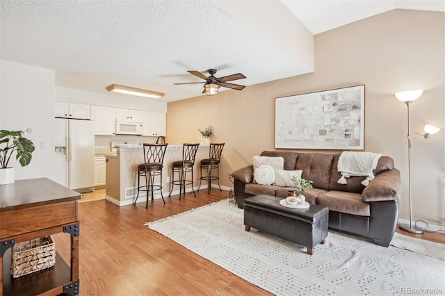 living room featuring lofted ceiling, light hardwood / wood-style flooring, and ceiling fan