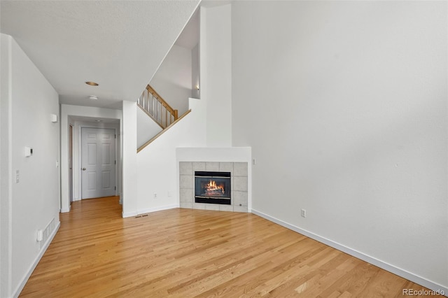 584 Ridgeview Dr, Louisville, CO 80027 - unfurnished living room with light wood finished floors, baseboards, a tiled fireplace, and stairs