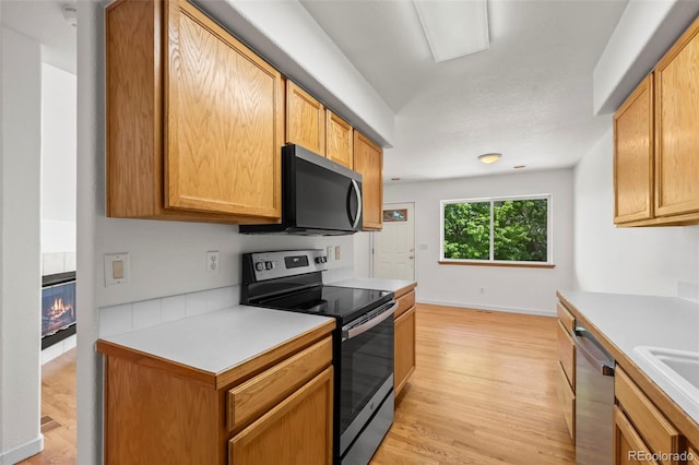584 Ridgeview Dr, Louisville, CO 80027 - kitchen featuring appliances with stainless steel finishes, light countertops, light wood finished floors, and a tile fireplace