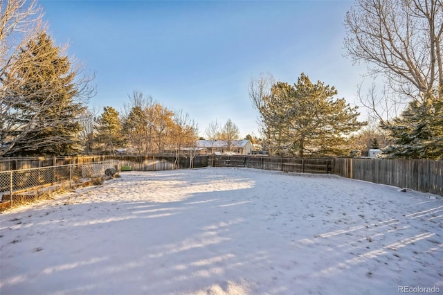 yard layered in snow with a fenced backyard