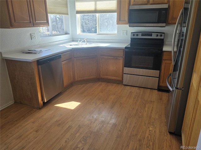 kitchen featuring light countertops, appliances with stainless steel finishes, light wood-type flooring, and a sink