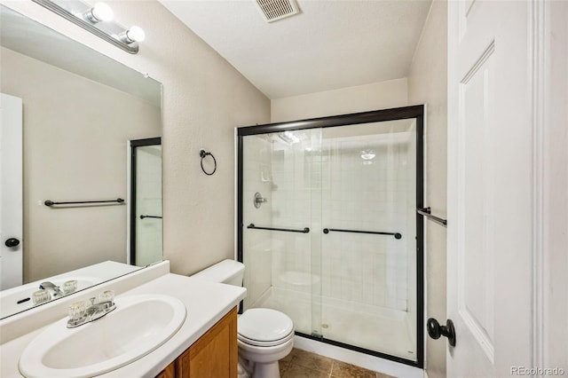 bathroom featuring visible vents, toilet, a stall shower, vanity, and tile patterned floors